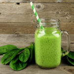 Healthy green smoothie with spinach in a jar mug on wood